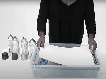 Art preparation with spray paint and paper in studio environment Woman preparing art materials with spray paint cans and paper in a studio setting