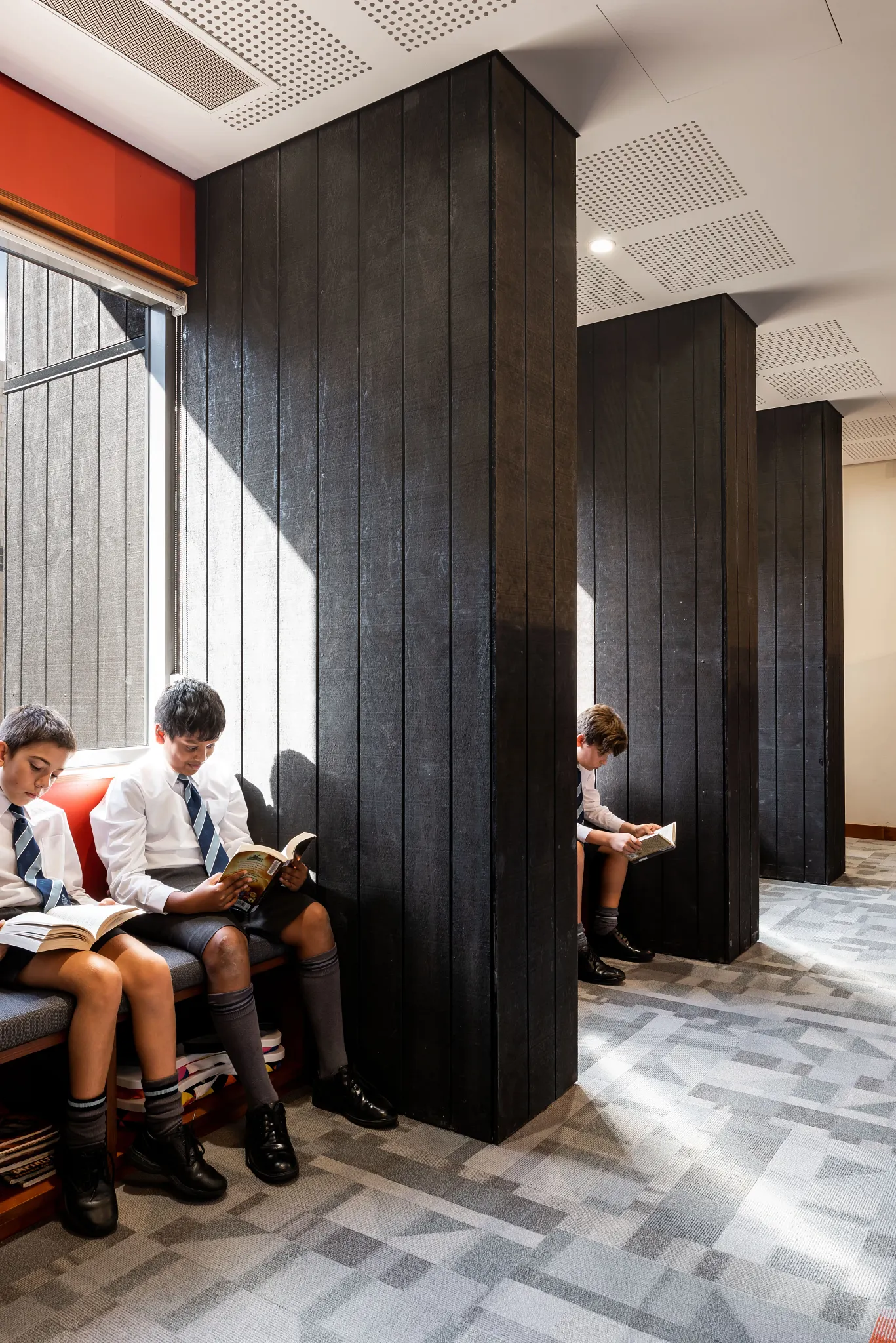 Education Facility with young students reading on benches, featuring geometric patterned commercial carpet tile flooring