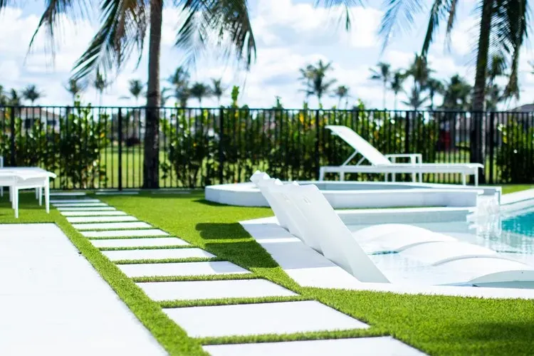 Modern outdoor pool area with white lounge chairs and green grass