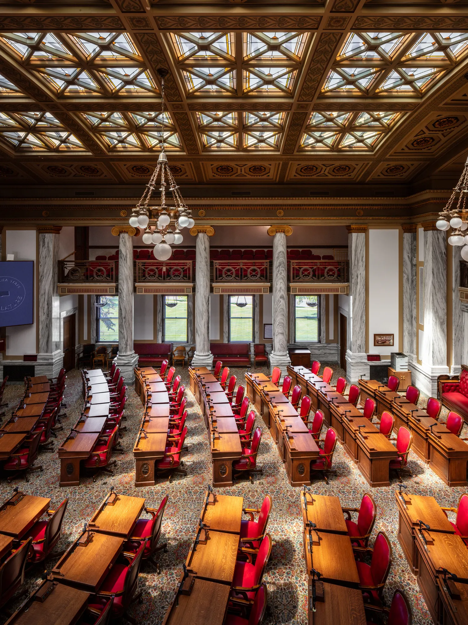 Ornate government facility with red chairs and wooden desks