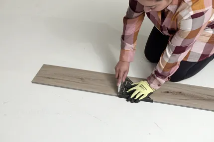 Wood-look flooring installation process Person installing wood-look flooring plank on white surface