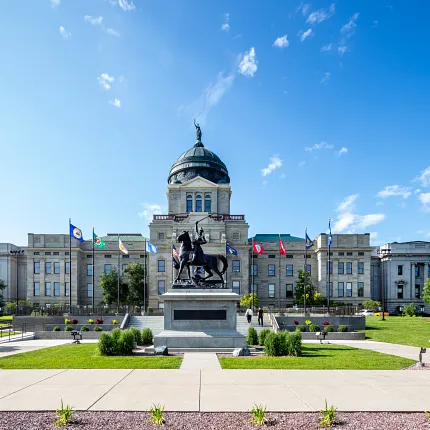 Majestic government facility with landscaped entrance Government building with flags and statue in front