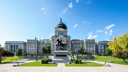Majestic government facility with landscaped entrance Government building with flags and statue in front