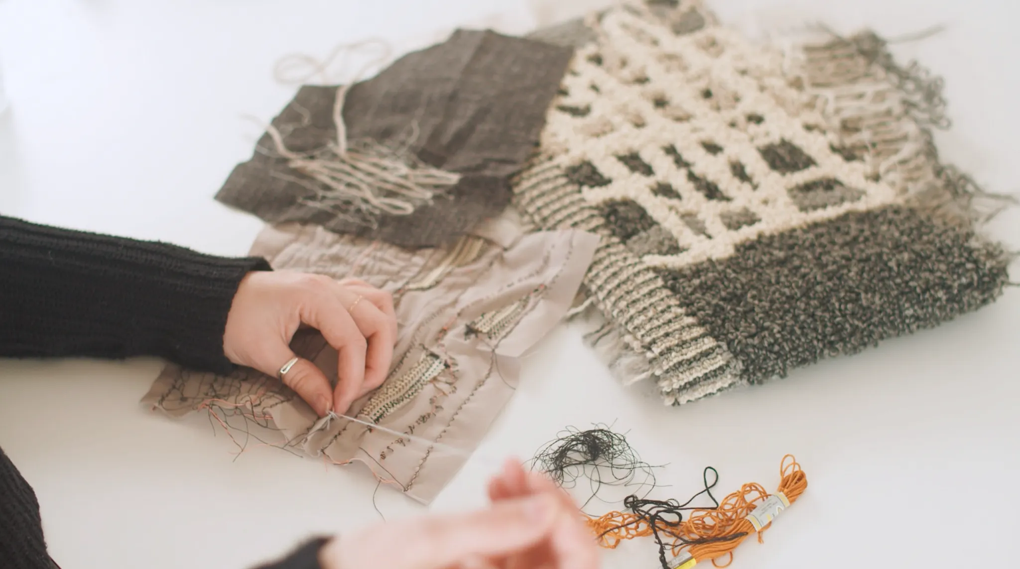 Close-up of hands working on textile samples with various textures and colors