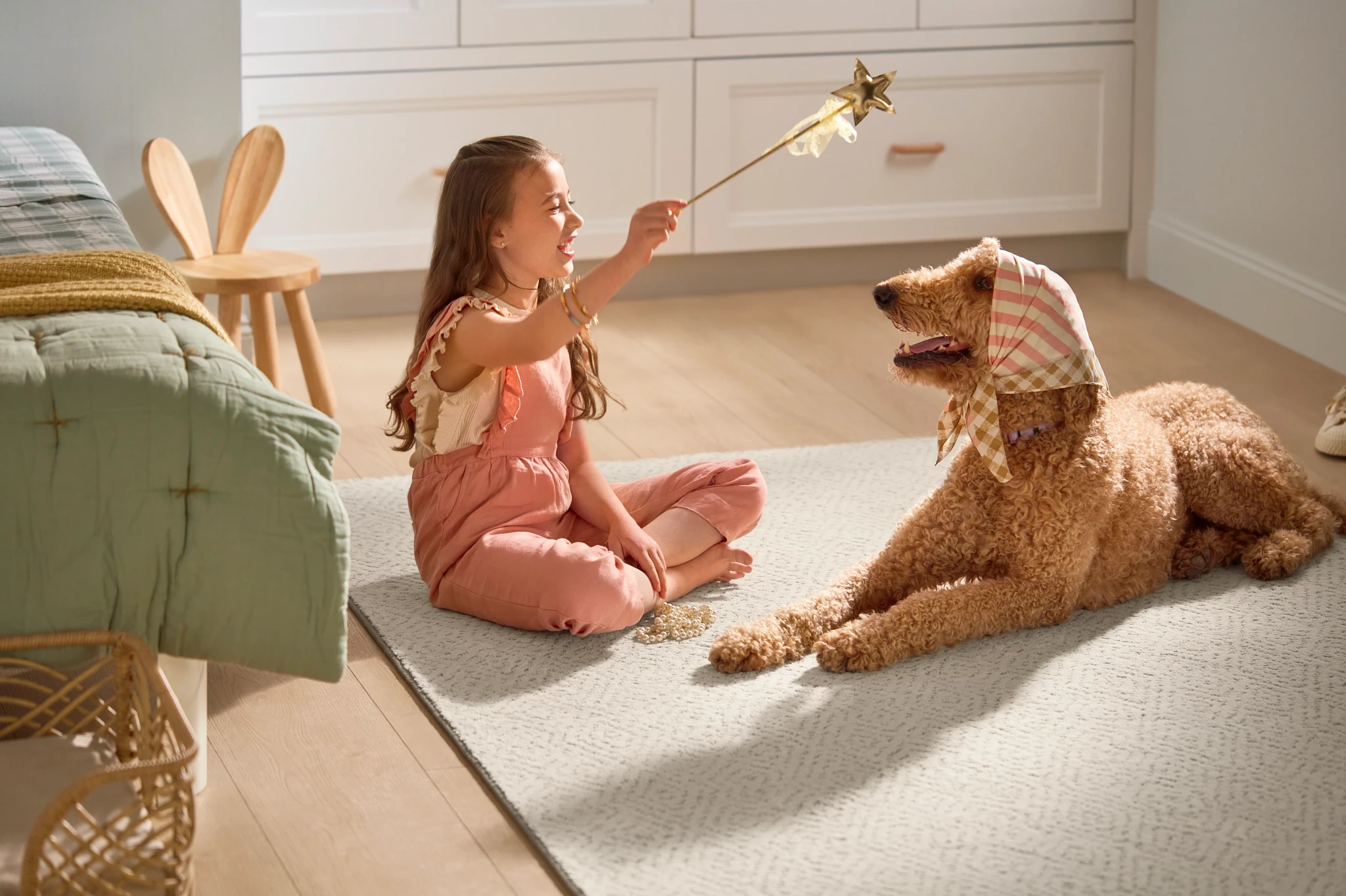 Girl playing with dog resting on beige soft surface flooring