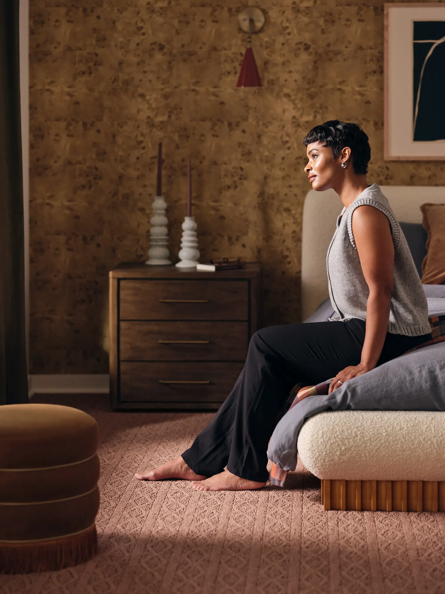 Cozy bedroom with synthetic carpet in a warm brown tone, featuring a woman sitting on a bed