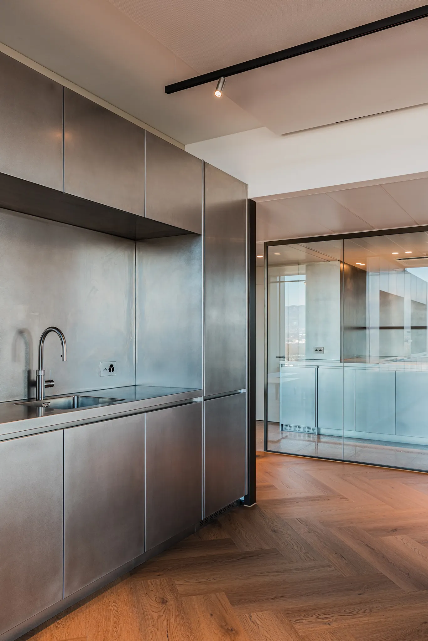 Inox kitchen in office with rich wood herringbone floor from Coretec