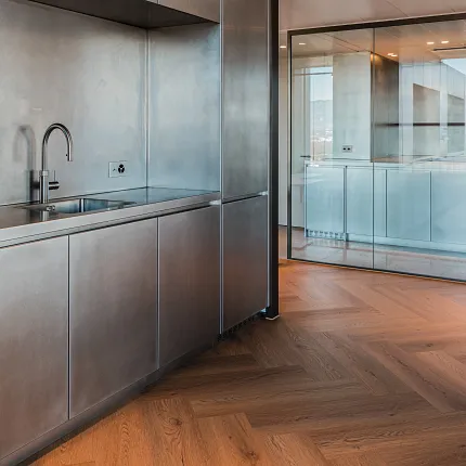 Inox kitchen in office with rich wood herringbone floor from Coretec