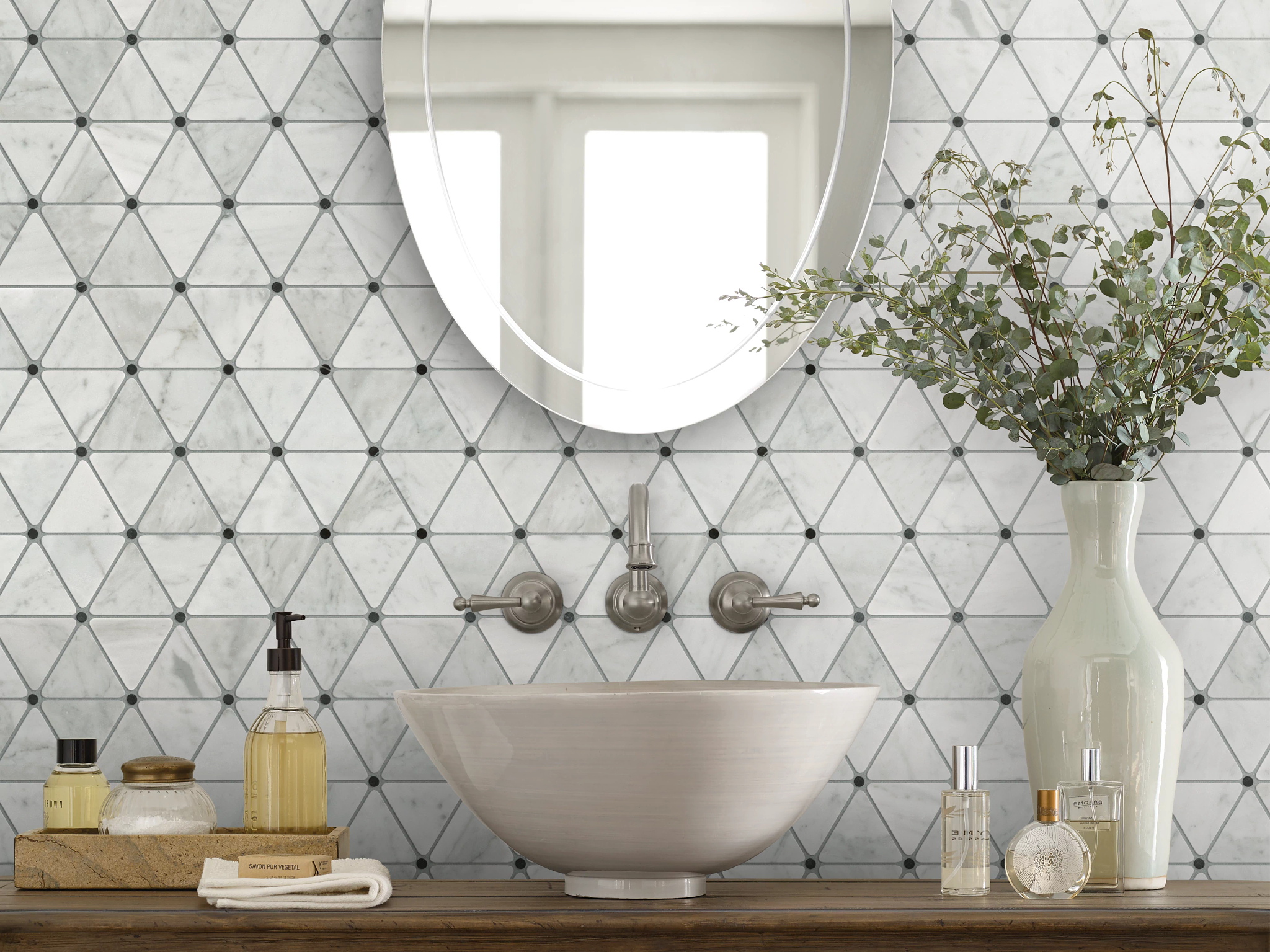 Triangular mosaic patterned tile behind a bathroom sink