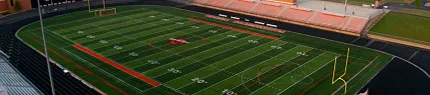 Artificial turf football field with stadium seating Aerial view of a football field with artificial turf
