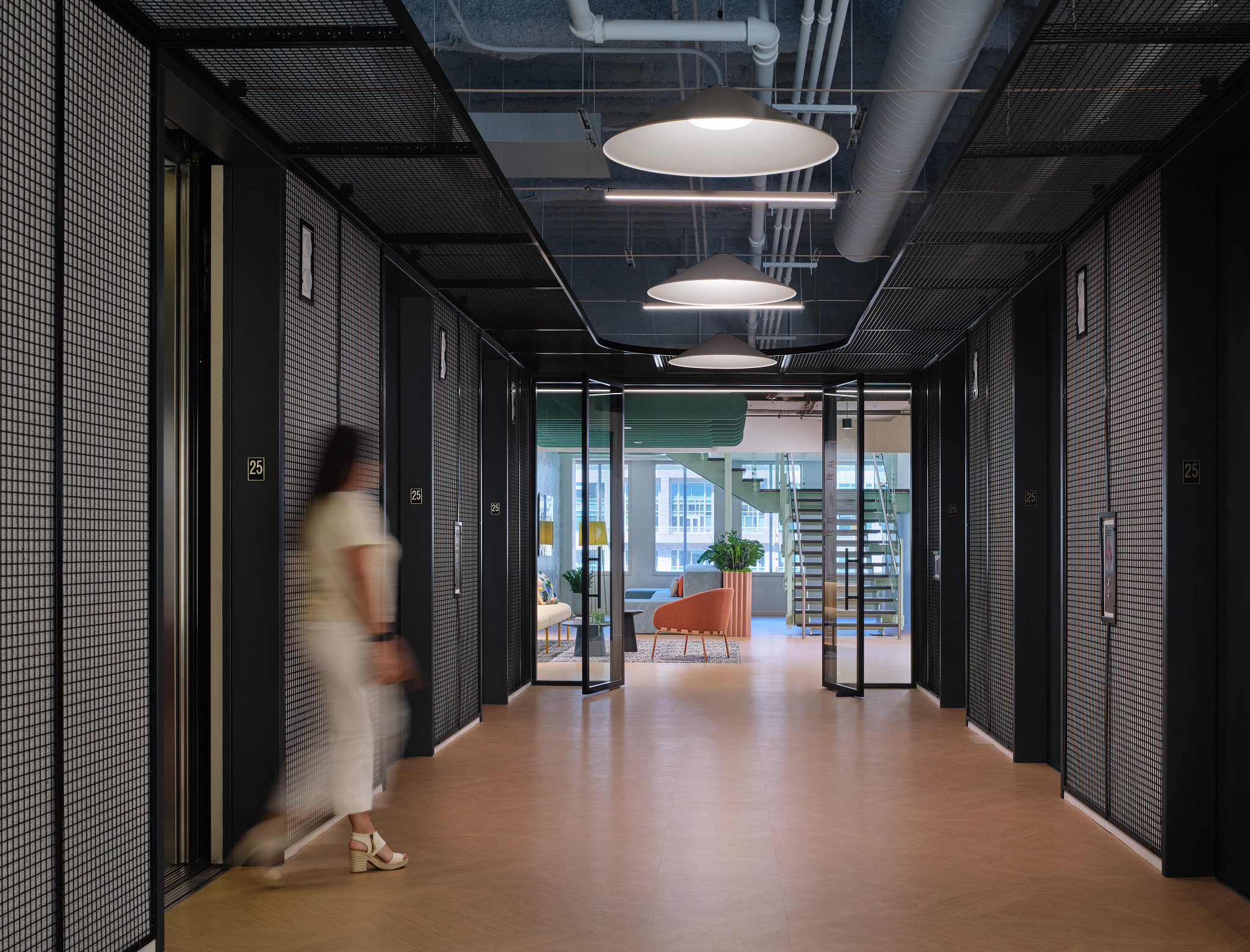 Modern workplace hallway with heavy commercial luxury vinyl tile flooring, featuring a woman walking past elevators, 18x18 inch dimensions, Workplace segment
