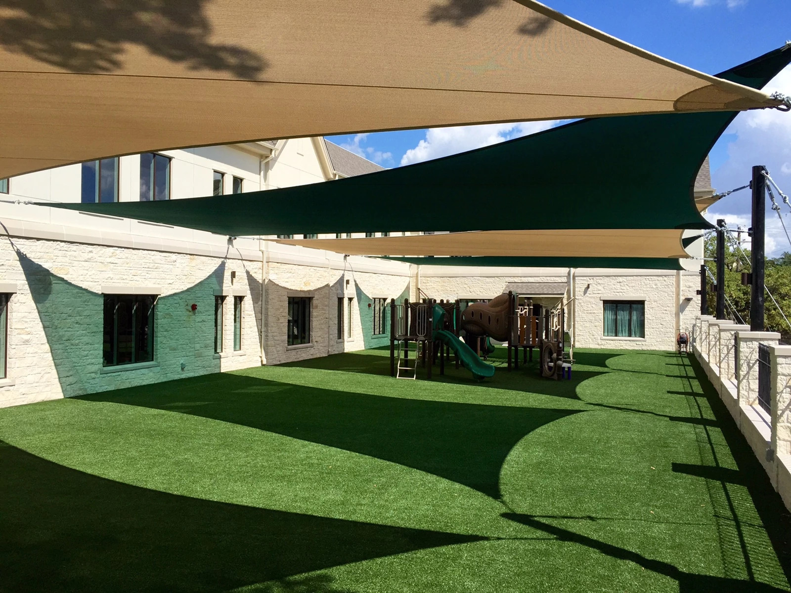 Outdoor playground with artificial grass flooring and shade sails
