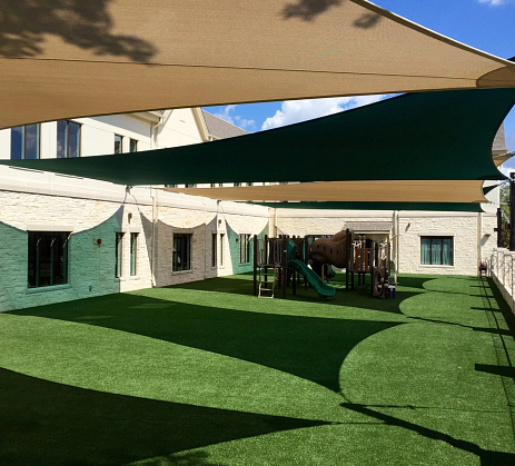 Sail shades covering a playround with turf.