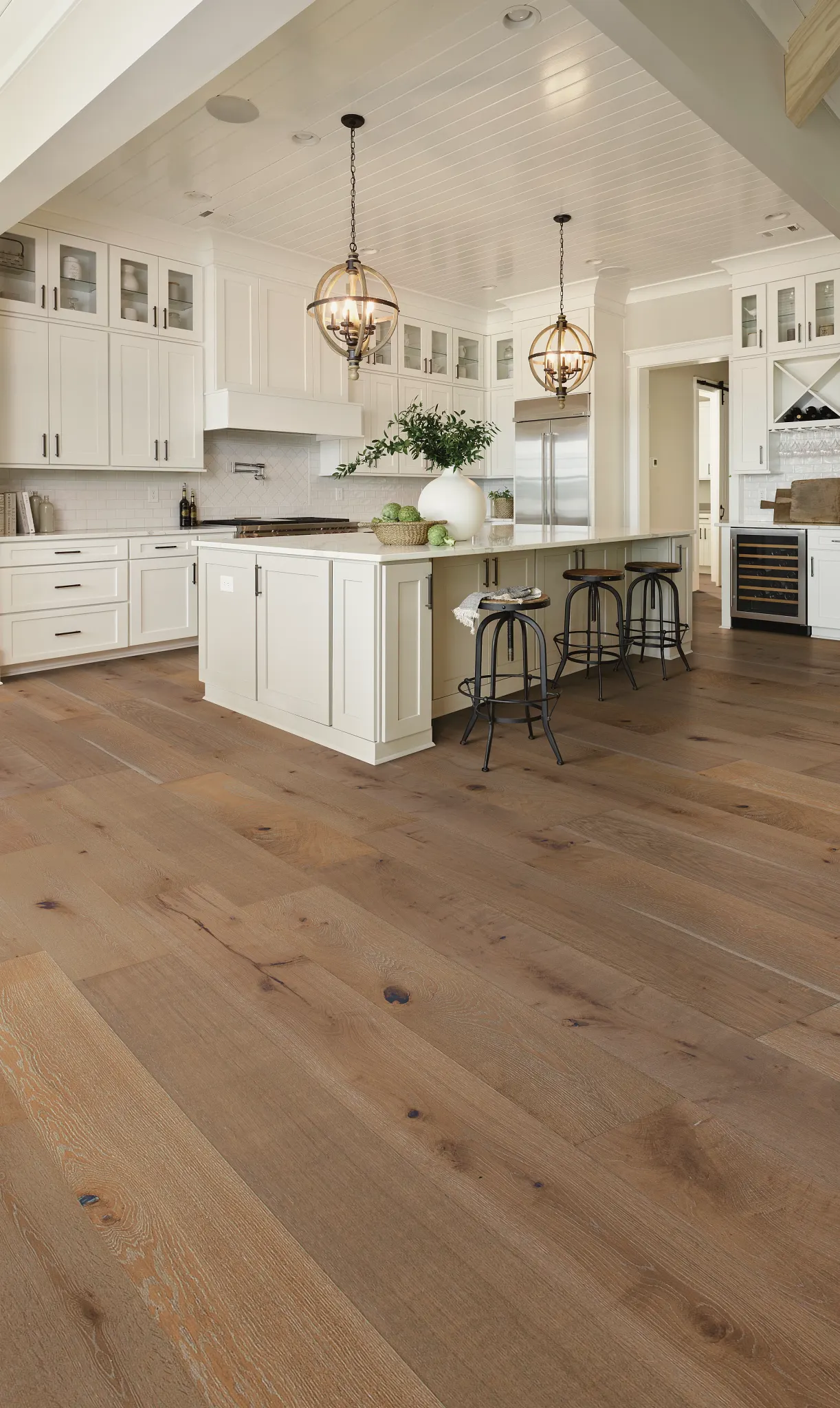 Modern kitchen with light oak engineered hardwood flooring, white cabinetry, and pendant lighting