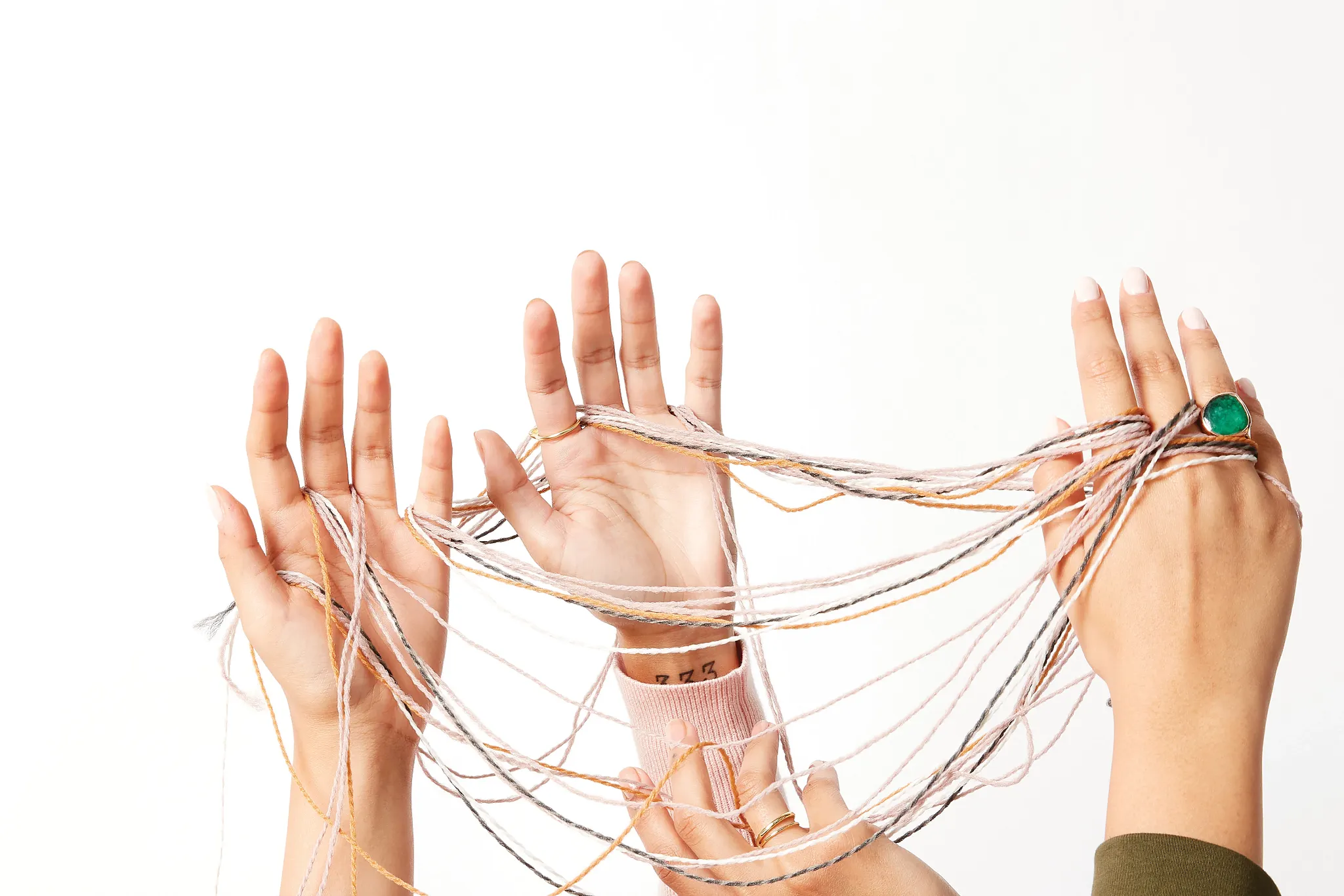 Hands holding colorful threads against a white background
