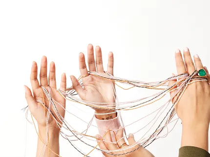 Hands with threads in artistic display Hands holding colorful threads against a white background