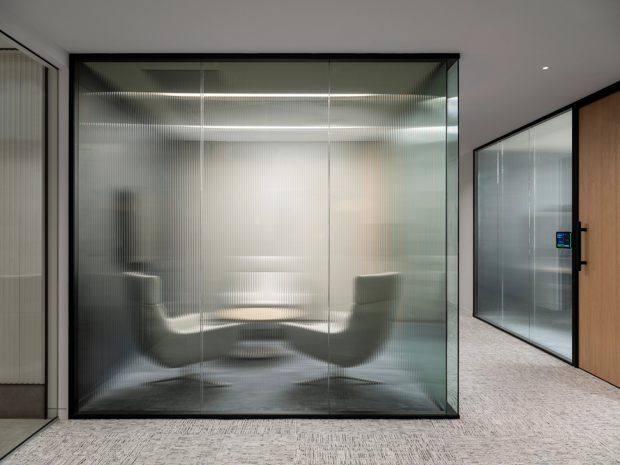 Modern workplace meeting room with frosted glass walls and commercial carpet flooring