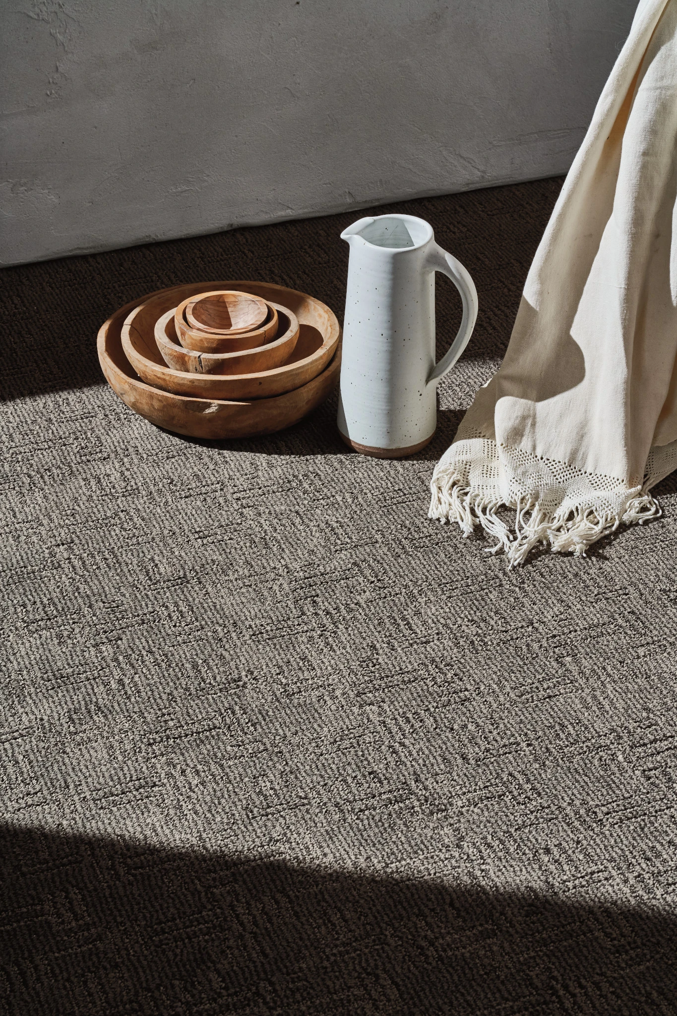 Textured beige carpet in a sunlit room with wooden bowls and a white pitcher