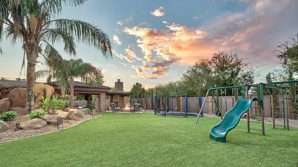Scenic backyard with synthetic turf and play area Outdoor playground with artificial grass and sunset sky