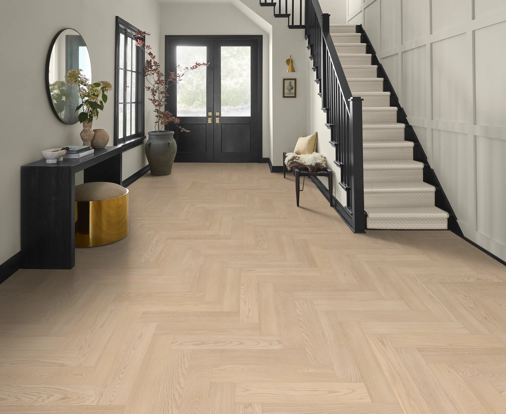 Modern entryway with light hardwood flooring and black staircase