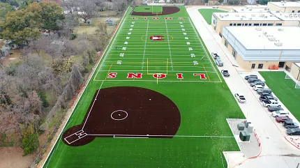Sports complex with artificial turf football field and baseball diamond Aerial view of a sports complex featuring artificial turf with a football field and baseball diamond