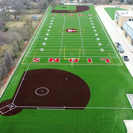 Sports complex with artificial turf football field and baseball diamond Aerial view of a sports complex featuring artificial turf with a football field and baseball diamond