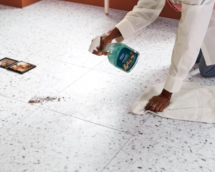 Terrazzo-Look Luxury Vinyl Tile Flooring - Coretec Residential SPC 37.01x18.5 inch Woman cleaning terrazzo-look luxury vinyl tile flooring with cleaning spray