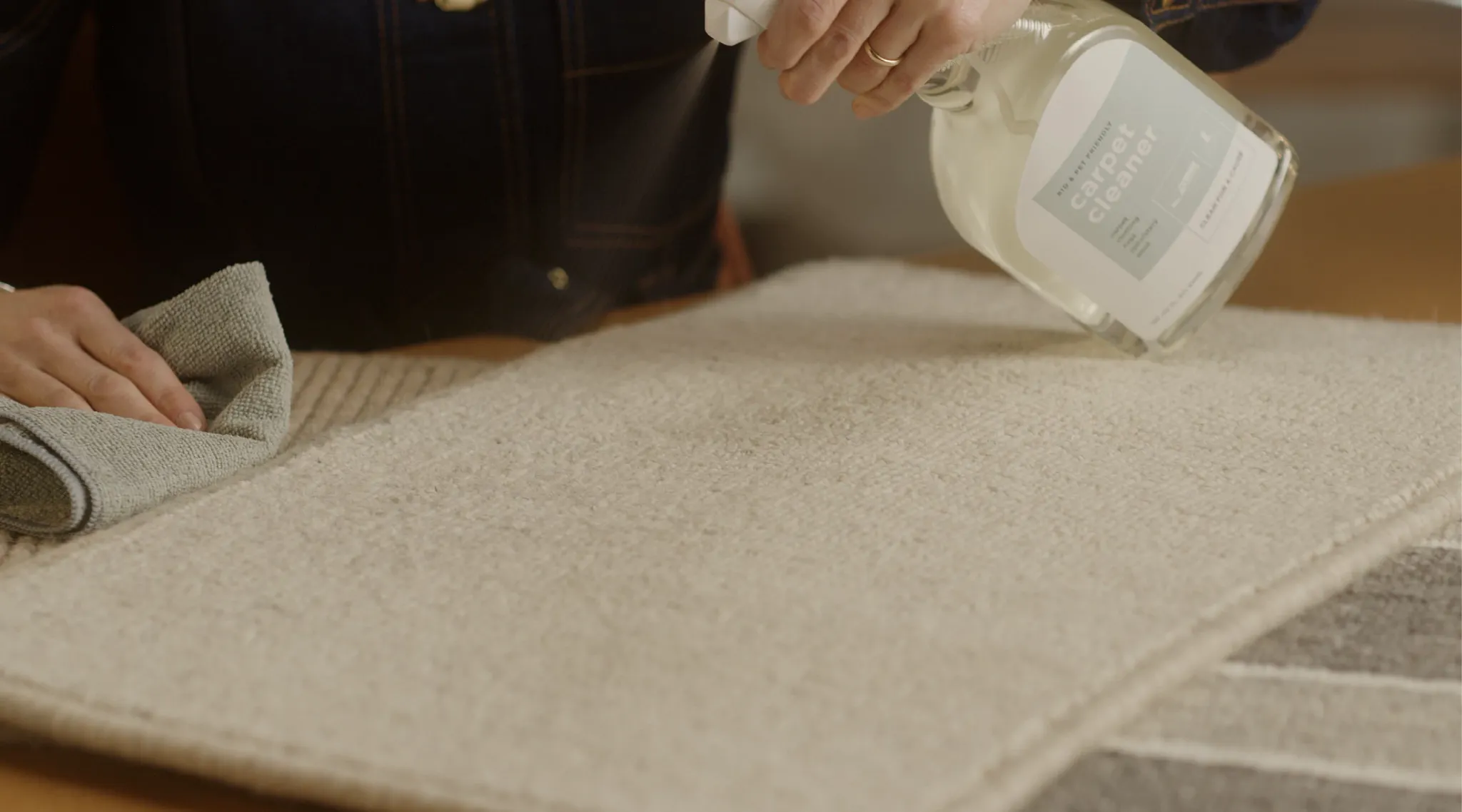 Person cleaning beige carpet with spray cleaner
