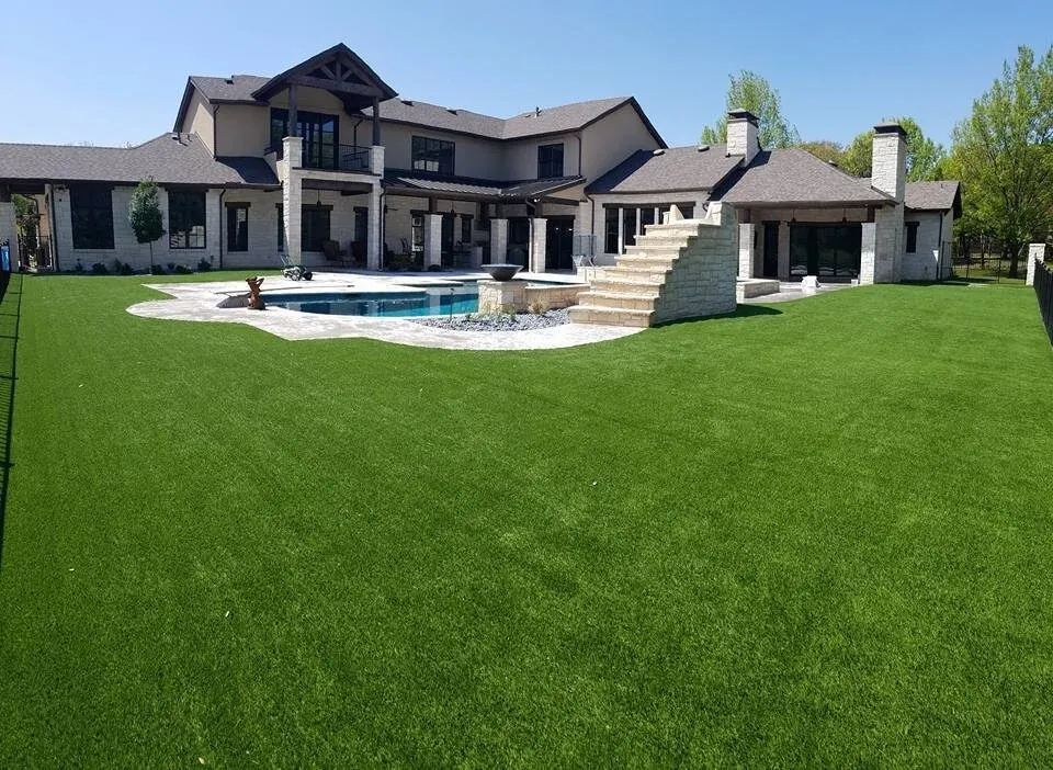 Expansive backyard with artificial grass and modern house