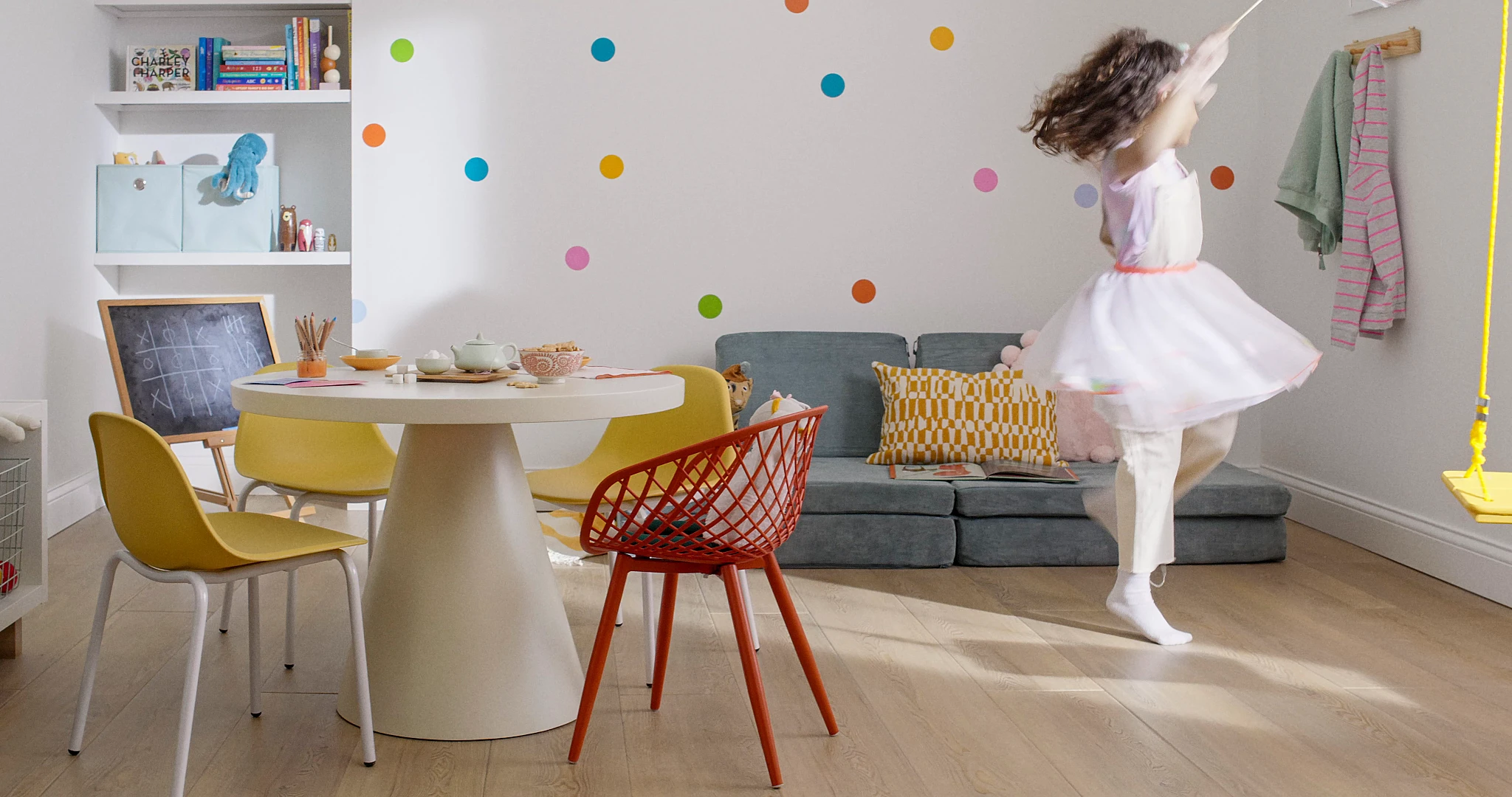 Modern playroom with a young girl dancing on wood look luxury vinyl plank flooring, featuring colorful chairs and wall decor.