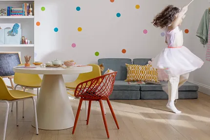 Wood Look Luxury Vinyl Plank Flooring in Playroom - Durable and Stylish Flooring Solution Modern playroom with a young girl dancing on wood look luxury vinyl plank flooring, featuring colorful chairs and wall decor.