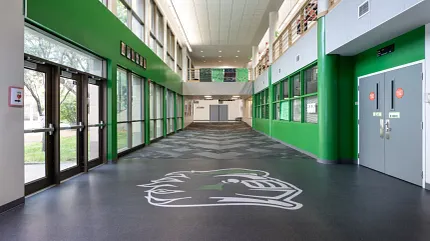 Durable flooring for educational spaces School hallway with dark flooring and green walls
