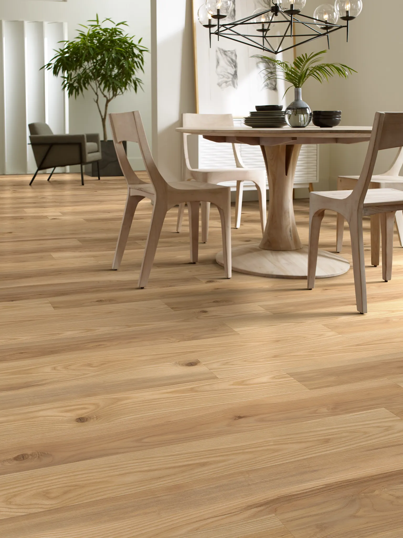 Modern dining room with light wood SPC flooring, featuring a round wooden table and chairs, and a contemporary chandelier