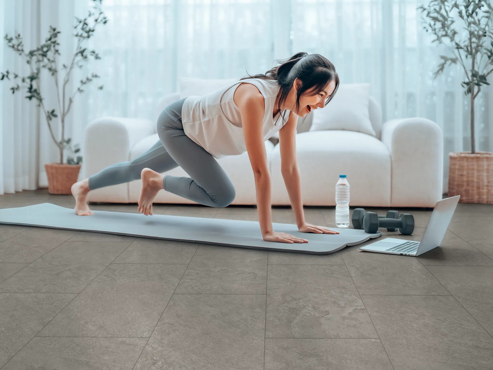 Woman on the floor on a yoga mat doing yoga while looking at ther laptop