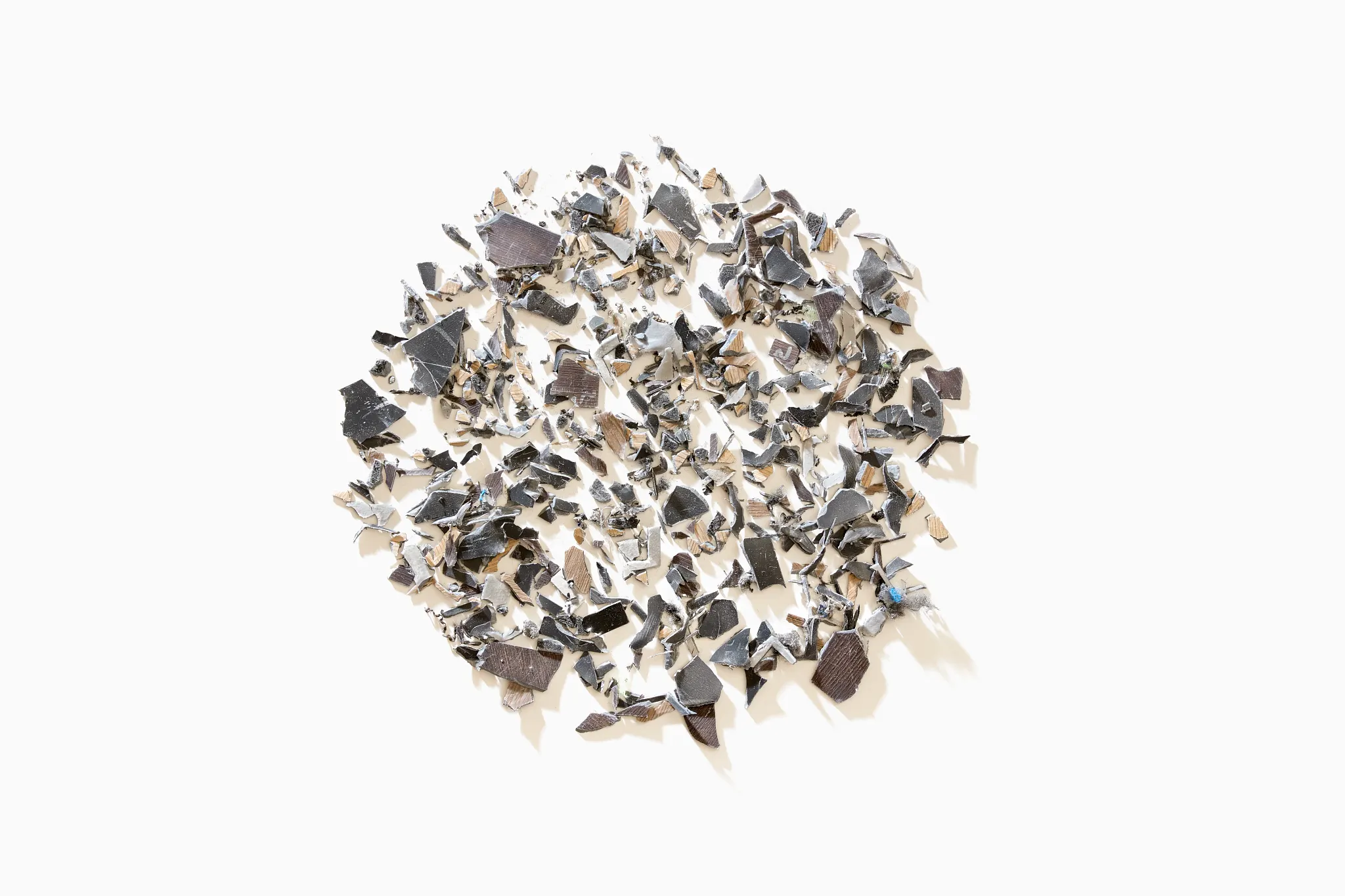 Close-up of a pile of mixed color flooring chips in shades of black, gray, and beige on a white background