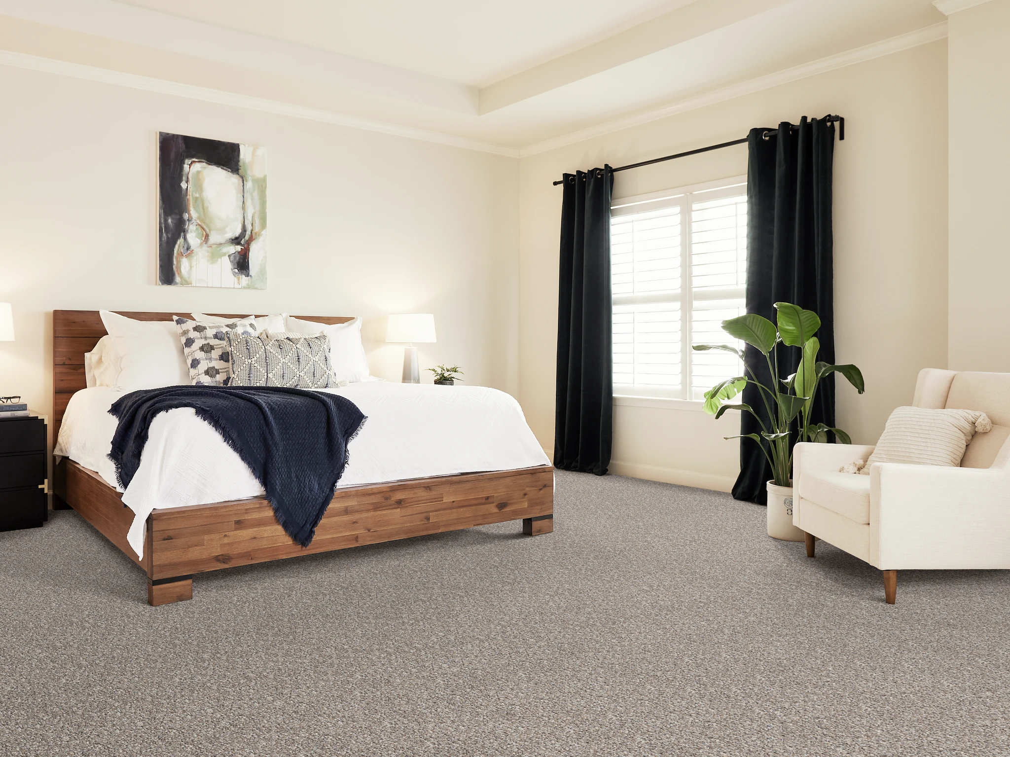 Cozy bedroom with patterned carpet flooring, featuring a wooden bed, white bedding, and a comfortable armchair