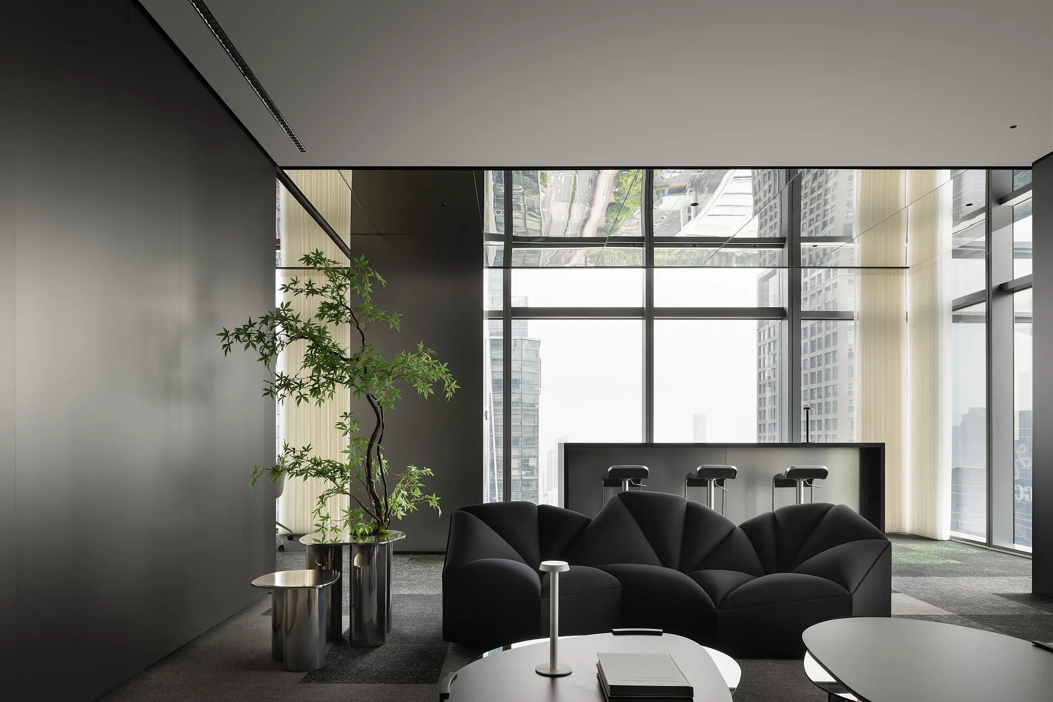 Modern office lounge with black furniture and large windows