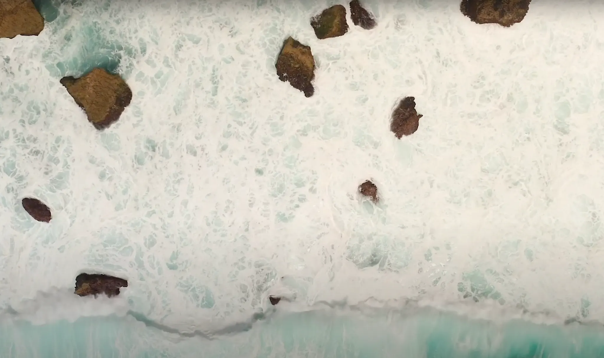 Aerial view of ocean waves crashing against rocks