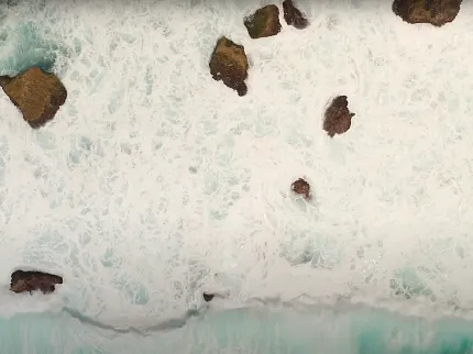 Ocean waves and rocks aerial view Aerial view of ocean waves crashing against rocks