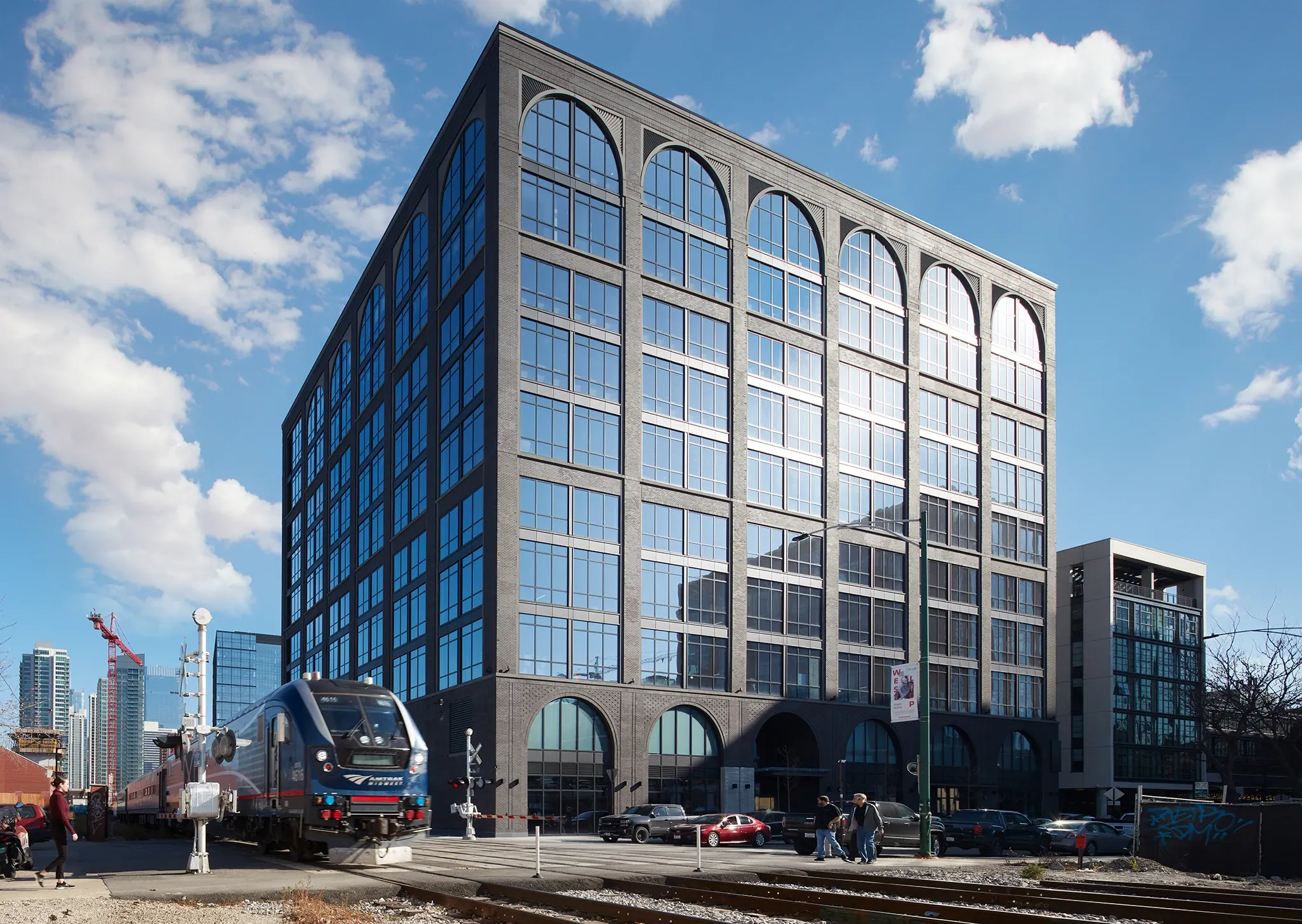 Modern office building with large arched windows and a train passing by