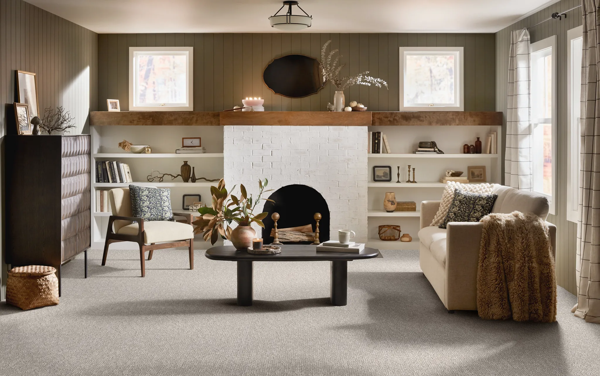 Cozy living room with neutral carpet flooring, featuring a white brick fireplace, modern furniture, and decorative elements for a warm and inviting atmosphere