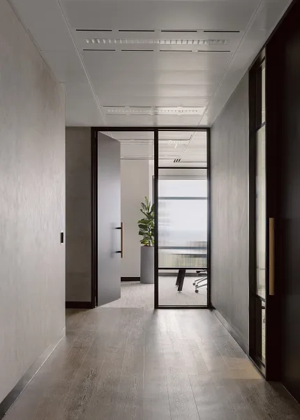 Contemporary Office Space with Elegant LVT Flooring Modern office hallway with sleek hardwood flooring and glass door leading to a meeting room with a potted plant