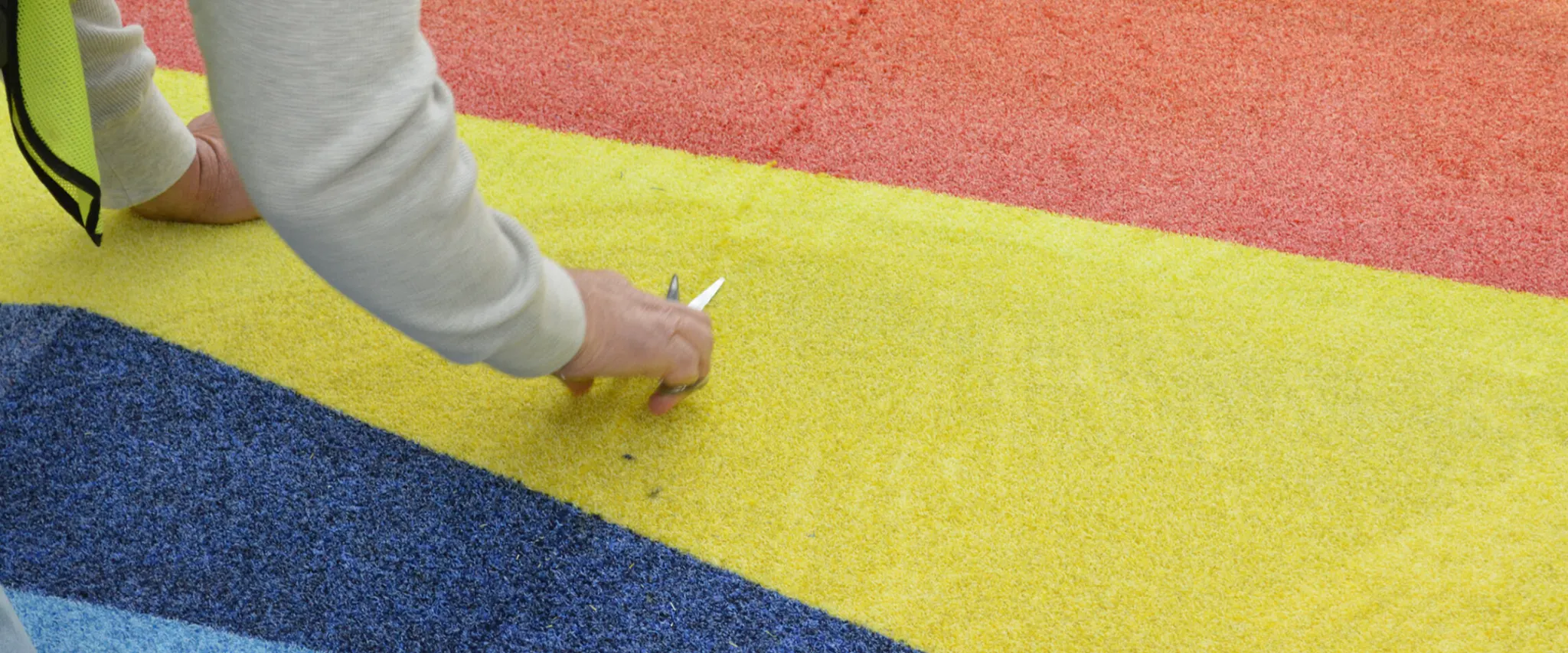 Person working on colorful carpet installation with red, yellow, and blue sections
