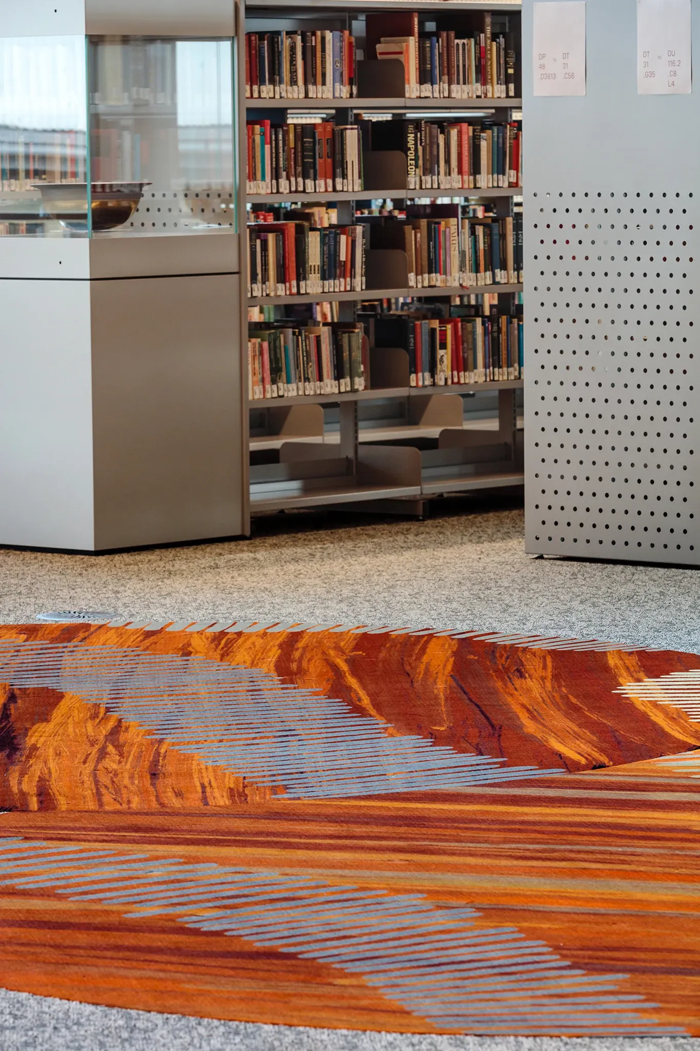 Custom patterned flooring installation within the University of Tasmania library, featuring organic forms and rich earthy tones inspired by Indigenous storytelling.
