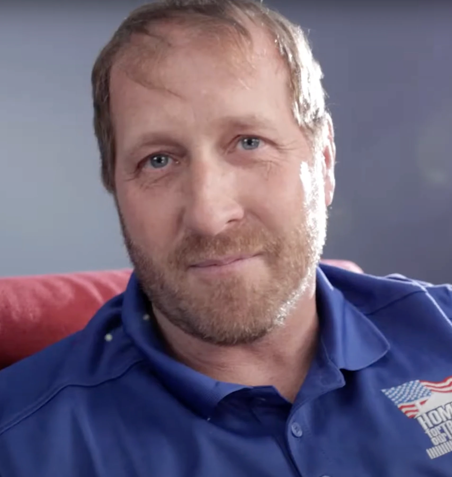 Man in blue shirt sitting on a red couch