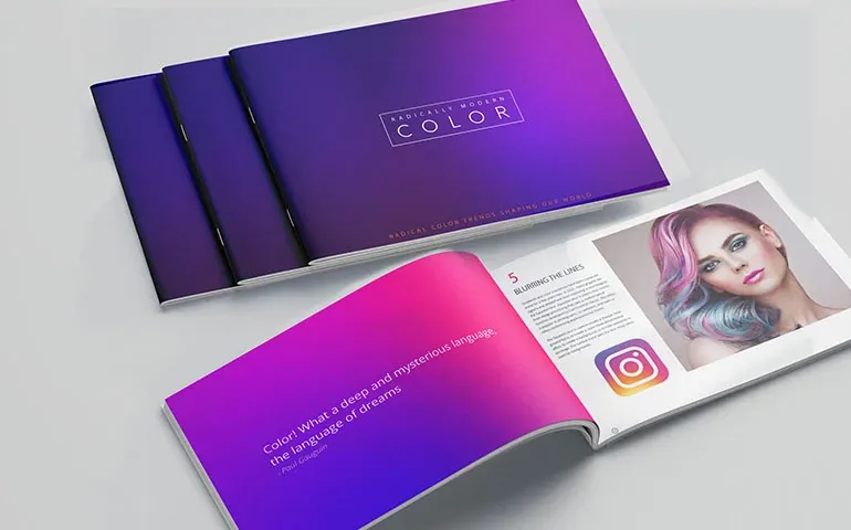 Opened and closed brochures with a gradient purple and pink cover on a light surface