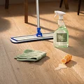 Easy-to-clean hardwood flooring for everyday comfort and durability Hardwood flooring with cleaning supplies including a mop, green towel, and hard surface cleaner