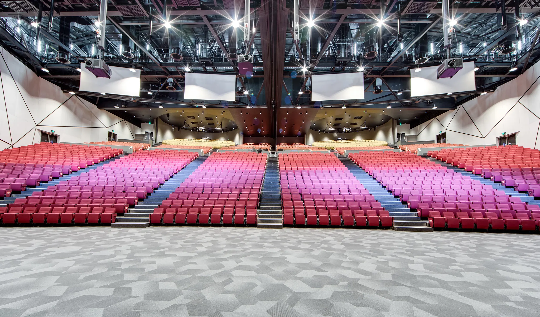 Auditorium with geometric patterned flooring and red seating