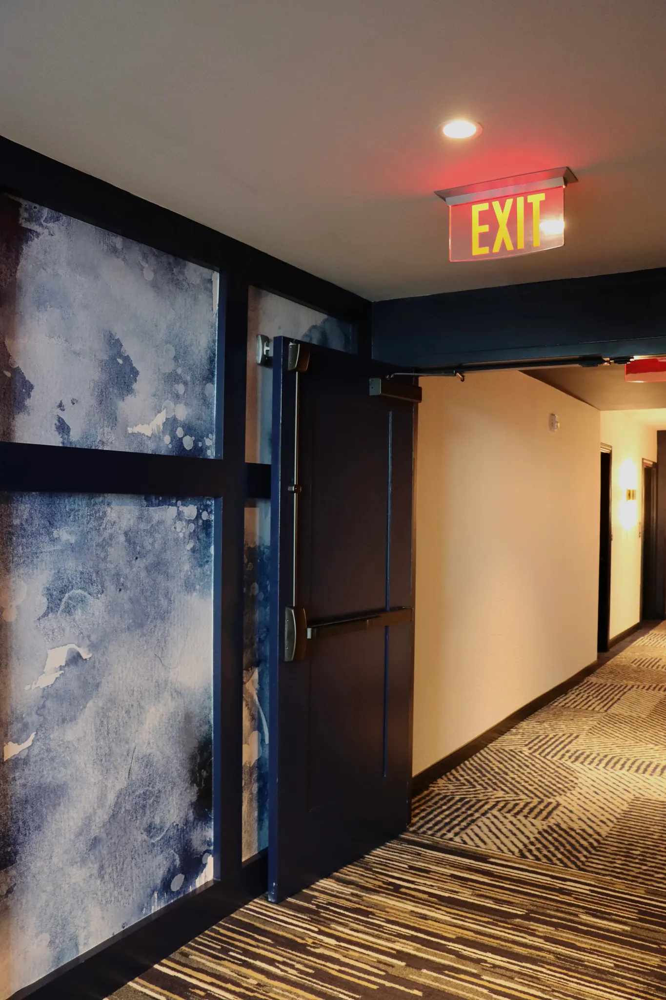 Modern hallway with abstract blue wall art and patterned carpet flooring