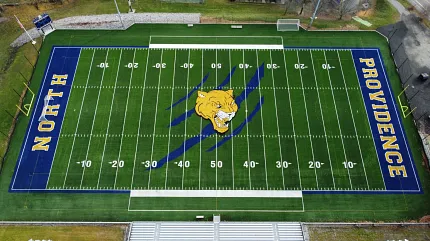 Artificial Turf Football Field with Lion Logo and Blue End Zones Aerial view of a football field with artificial turf featuring a large yellow lion logo at the center